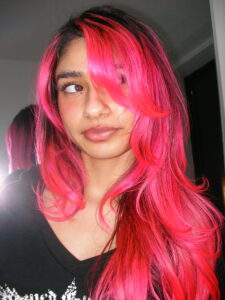Vibrant flamingo pink hair with natural dark shadow roots. High-contrast hair color trend 2026.